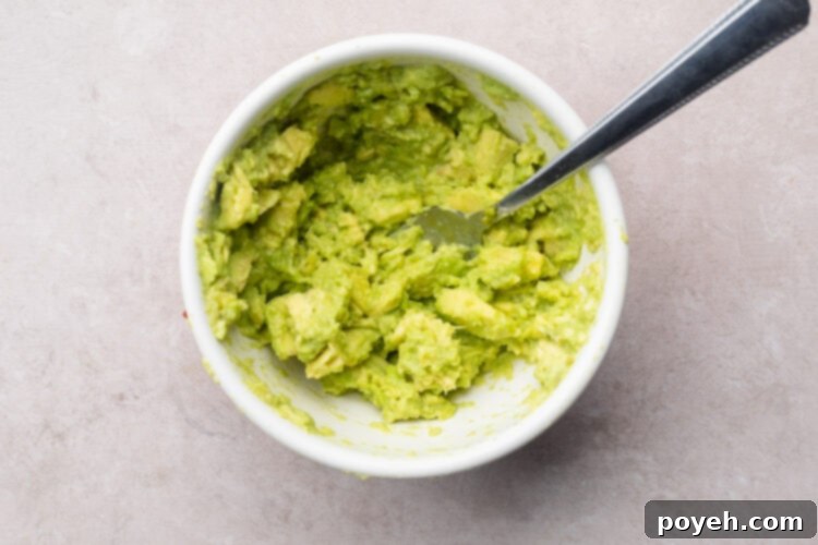 Guacamole in small white mixing bowl with a fork.