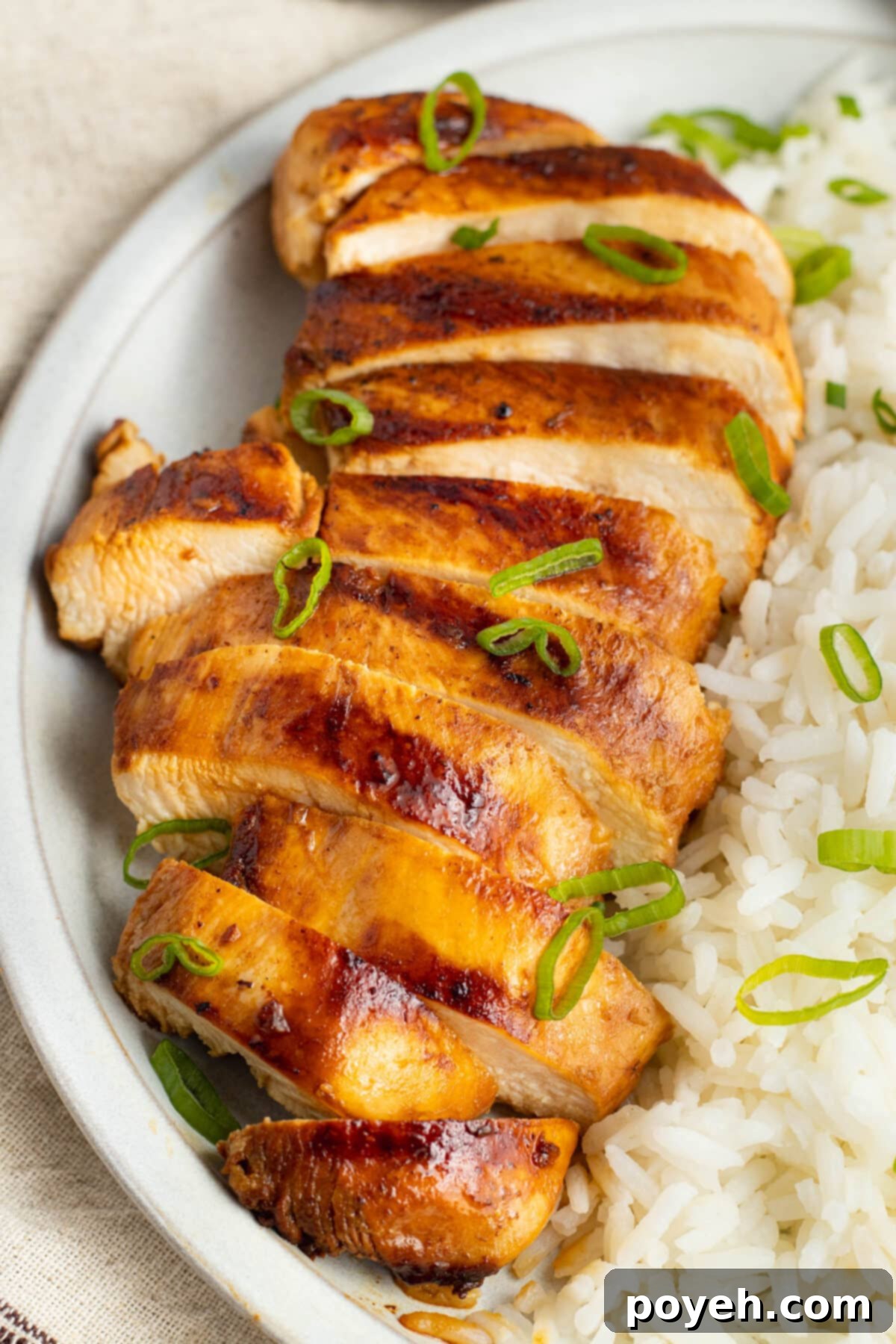 Top-down view of grilled chicken adobo, sliced and arranged on a platter with rice, garnished with green onions.