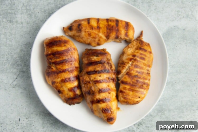 Grilled adobo chicken on a large round white plate.
