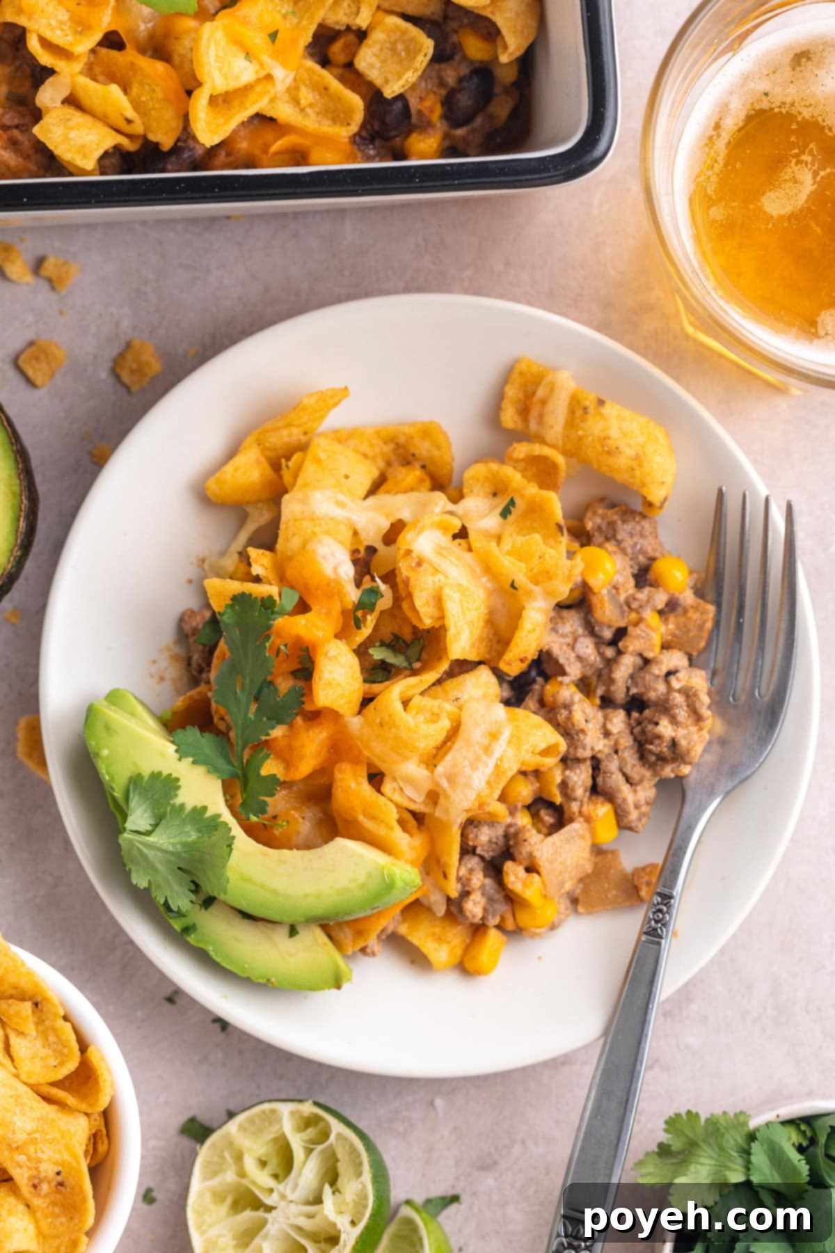 A serving of walking taco casserole on a round white plate with a silver fork.