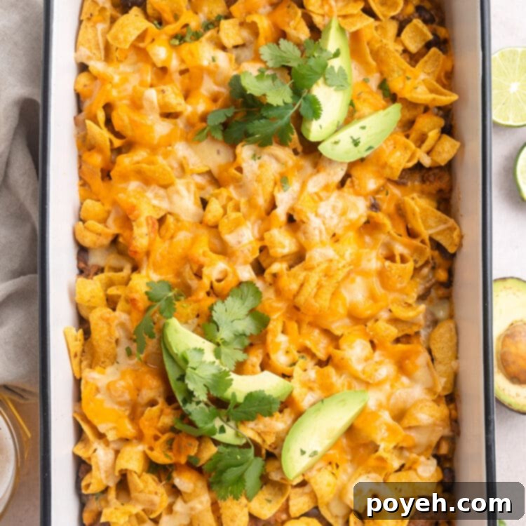 Walking taco casserole in a rectangular white casserole dish. A scoop is missing.