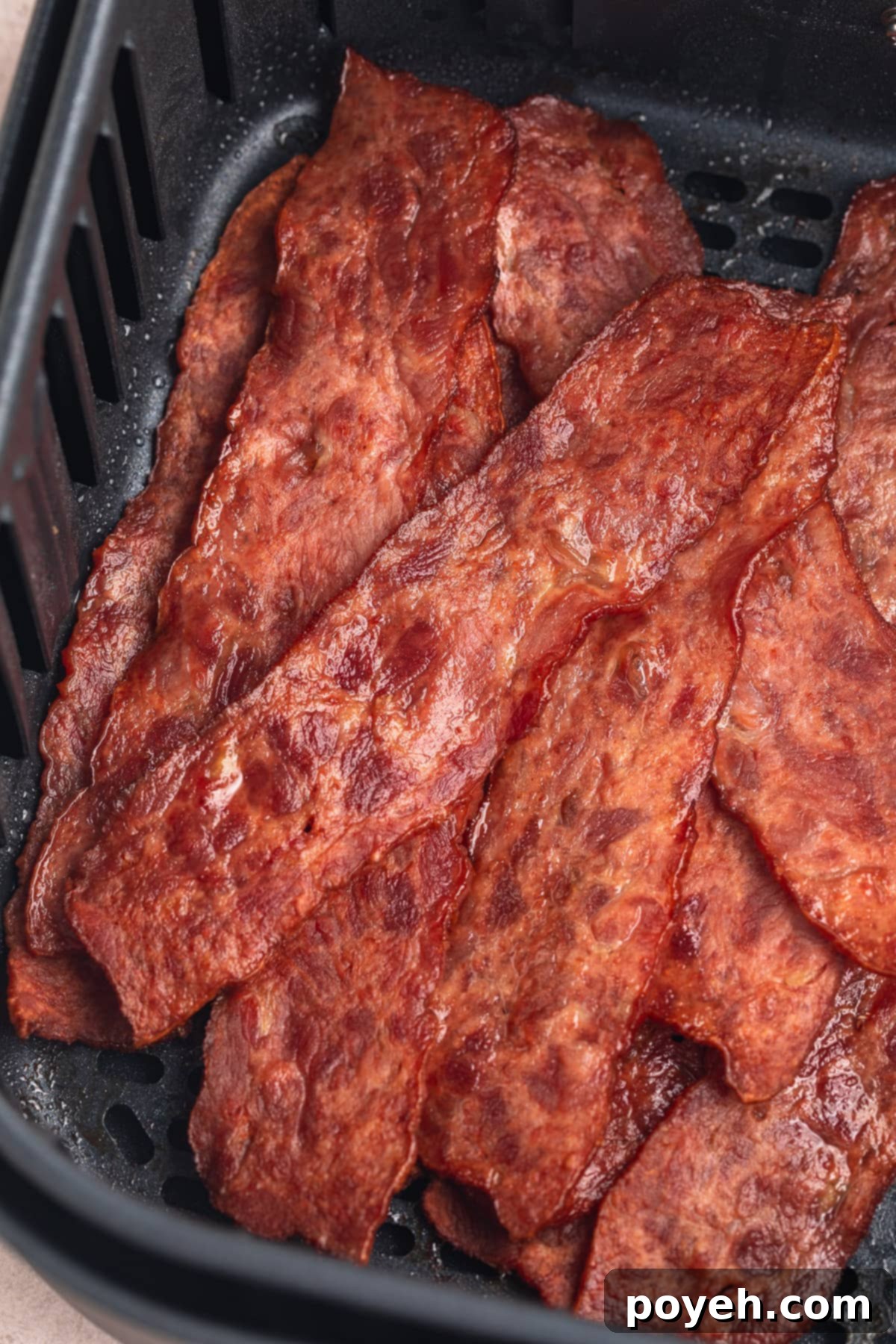Top-down view of strips of crispy turkey bacon in an air fryer basket.