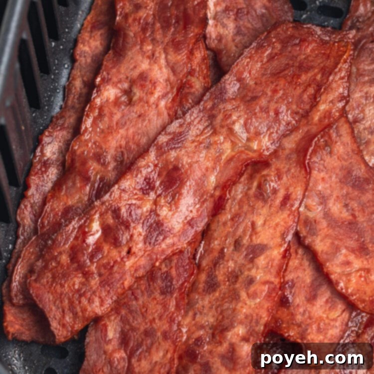 Top-down view of strips of crispy turkey bacon in an air fryer basket.