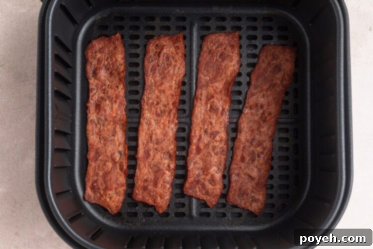 Strips of turkey bacon in air fryer basket.