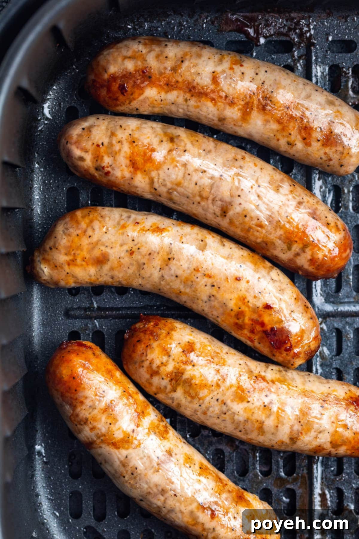 Overhead view of 5 Italian sausages in an air fryer basket.