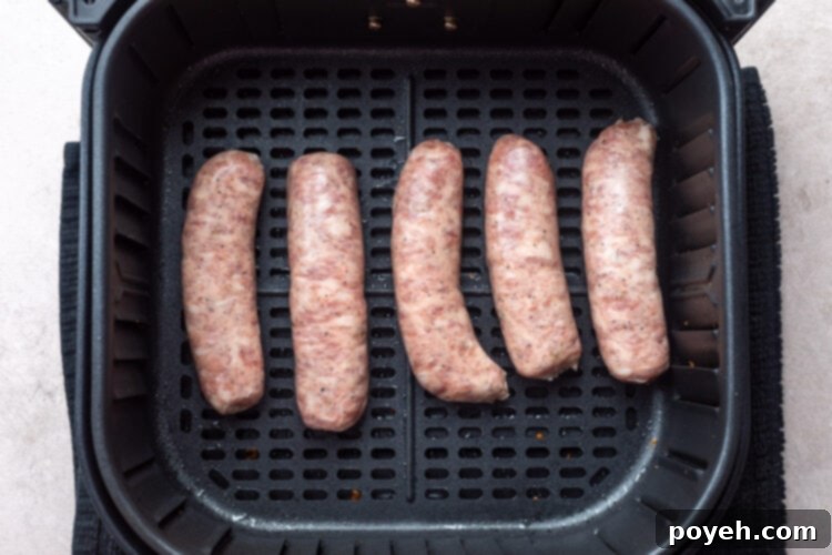 5 uncooked Italian sausage links in an air fryer basket.