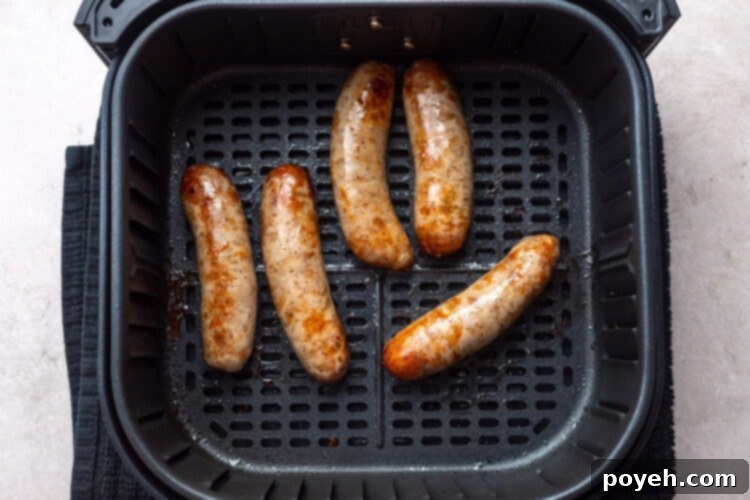 5 cooked Italian sausages in an air fryer basket.