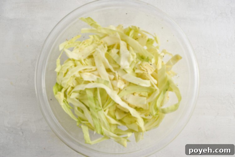 Simple homemade slaw with shredded cabbage in a medium glass mixing bowl.