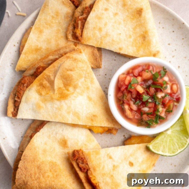 Crispy, golden-brown, triangle-shaped quesadilla slices on a plate with a ramekin of chunky pico de gallo.
