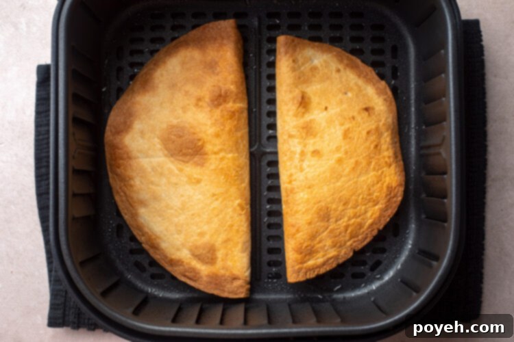 Two golden, crispy quesadillas in an air fryer basket.