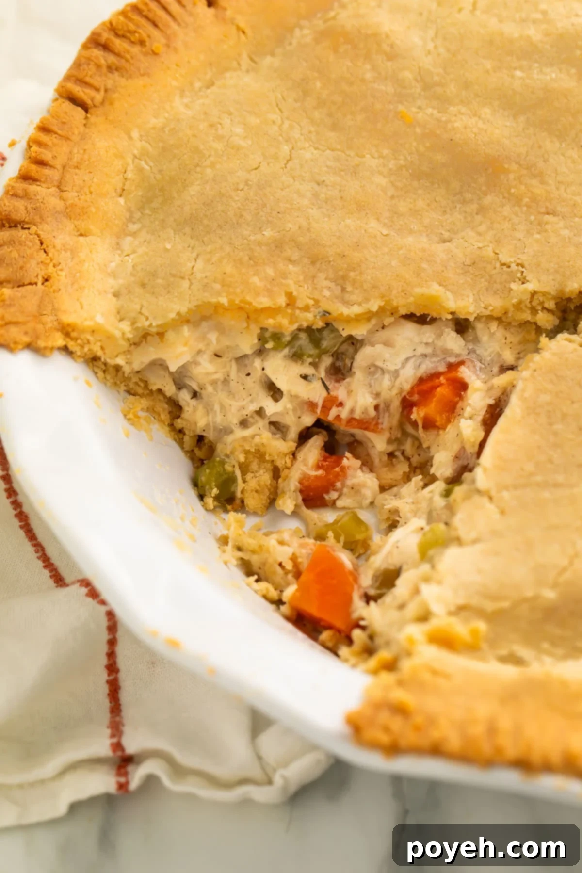 A close-up look at a gluten free chicken pot pie with a triangular slice of pie taken out of the pie plate.