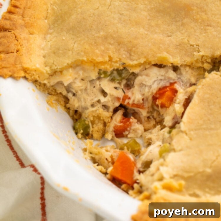 A close-up look at a gluten free chicken pot pie with a triangular slice of pie taken out of the pie plate.