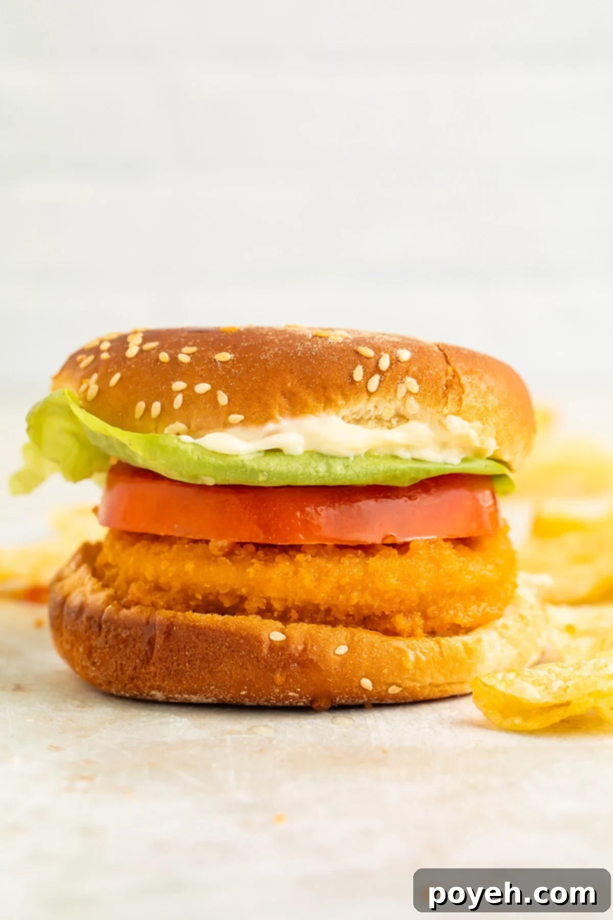 An air fryer chicken patty on a bun with a thick slice of tomato and lettuce.