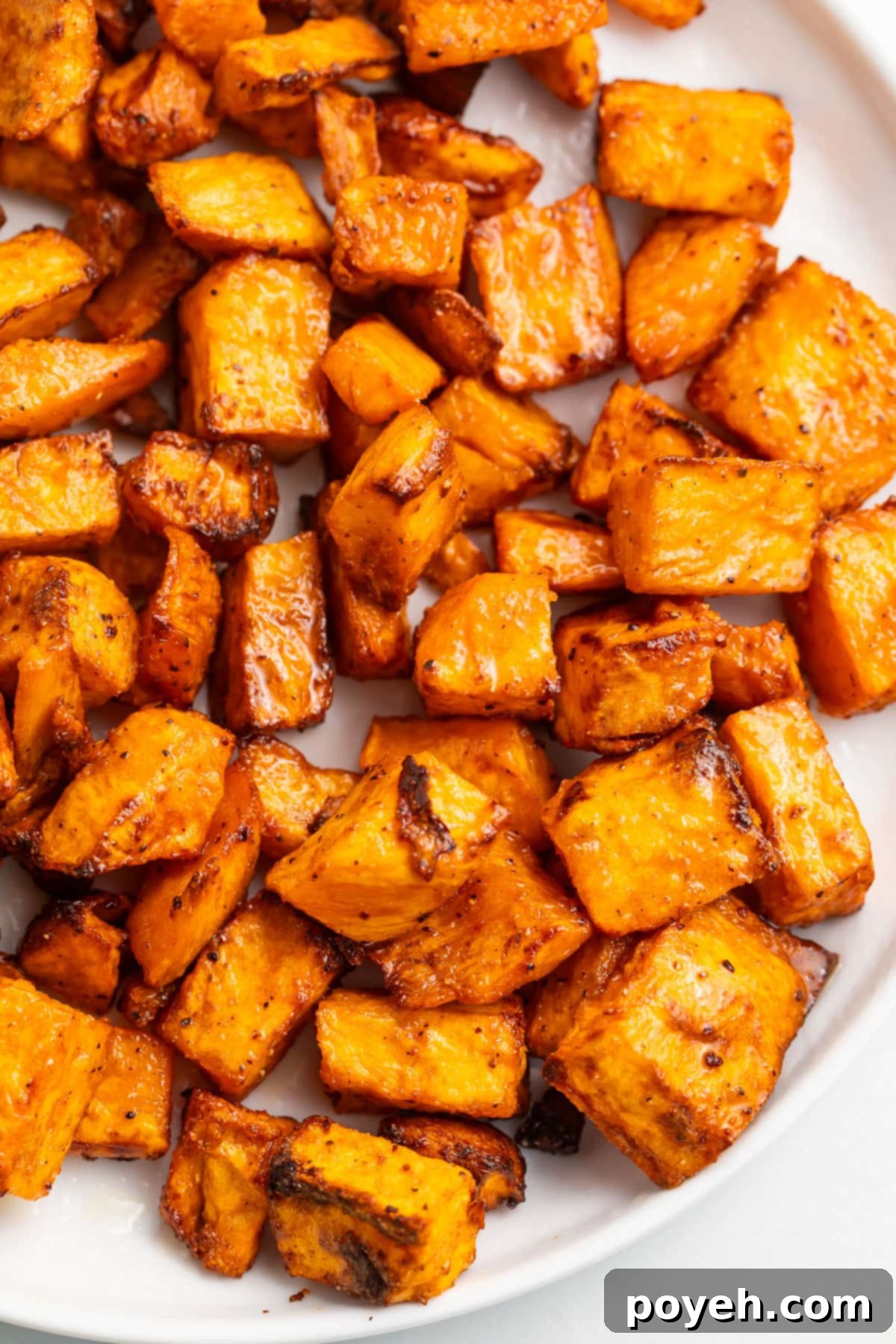 Crispy air fryer sweet potato cubes artfully arranged on a clean white plate, ready to be served.