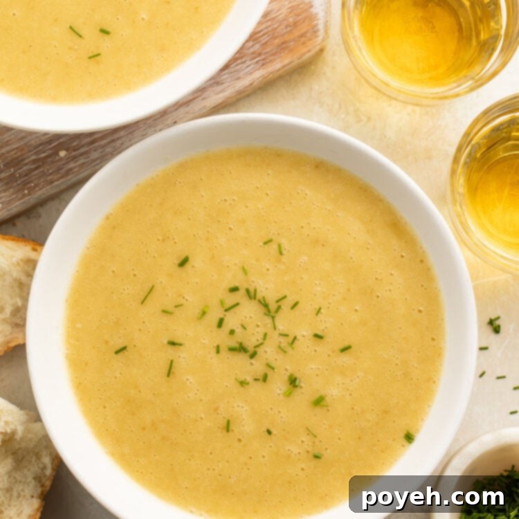 Bowls of yellow, creamy potato leek soup cooked in an Instant Pot on a table top with pieces of crusty bread surrounding.