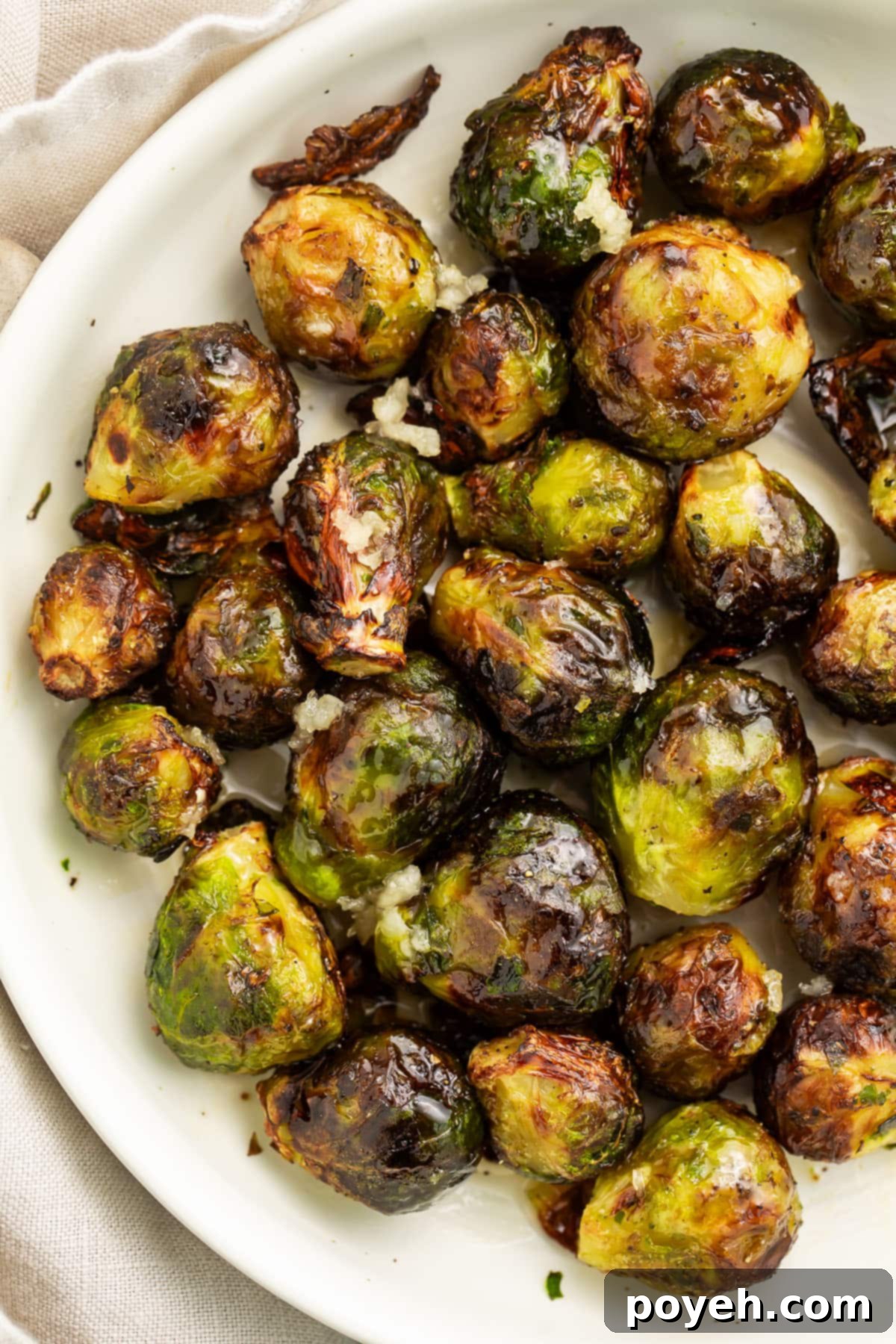 Air fryer frozen brussels sprouts on a large white plate, garnished and ready to serve.
