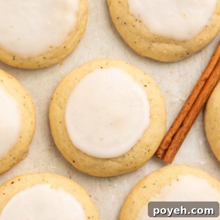 Close-up of a chai cookie made from Taylor Swift's recipe surrounded by other cookies flat on parchment paper, next to a cinnamon stick.