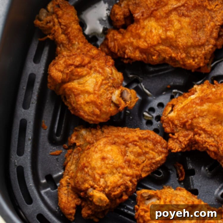 Crispy reheated fried chicken legs, thighs, and breasts in an air fryer basket.