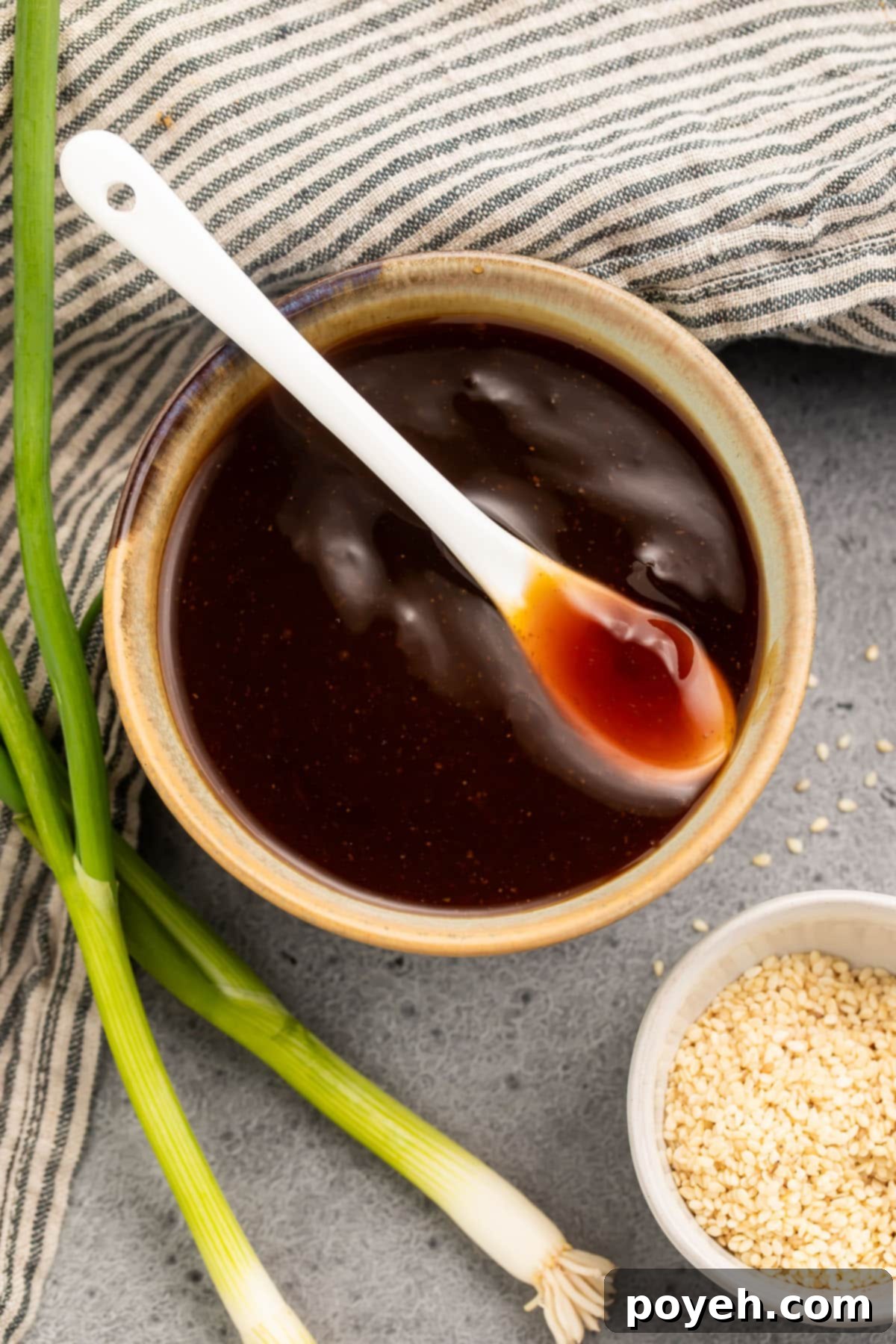 Overhead view of a bowl of gluten free teriyaki sauce with a white spoon resting in the bowl.