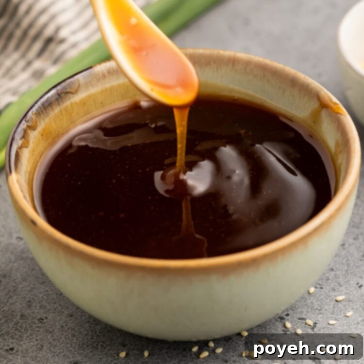 Gluten free teriyaki sauce being poured off a small white spoon into a bowl of teriyaki sauce.