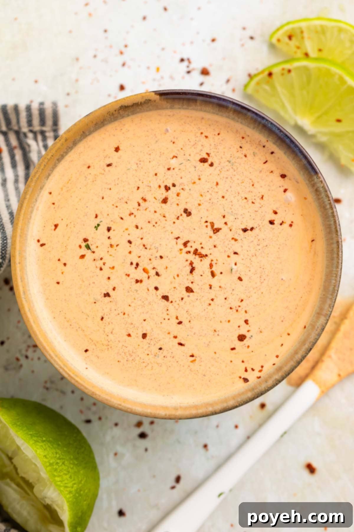 Overhead view of a beautiful peach-colored creamy Southwest salad dressing, artfully topped with a sprinkle of smoked paprika and a fresh cilantro sprig, presented in a rustic medium-sized bowl.