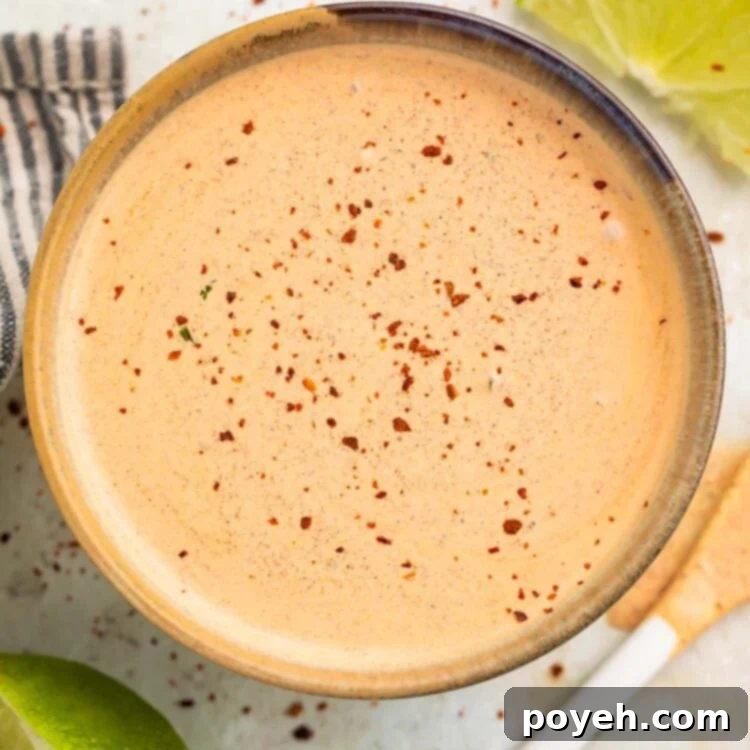 Overhead view of a peach-colored Southwest salad dressing, garnished with a sprinkle of smoked paprika and a fresh cilantro sprig, presented in a delightful medium bowl.