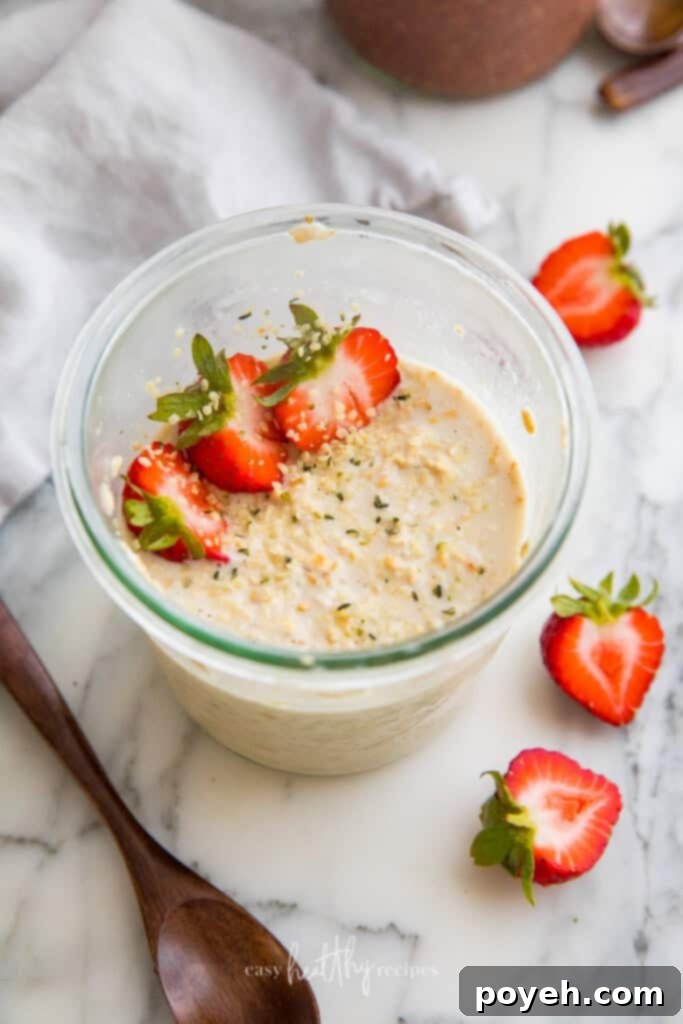 A jar of classic vegan overnight oats topped with fresh, vibrant strawberries and a sprinkle of chia seeds, highlighting its simple yet appealing presentation.
