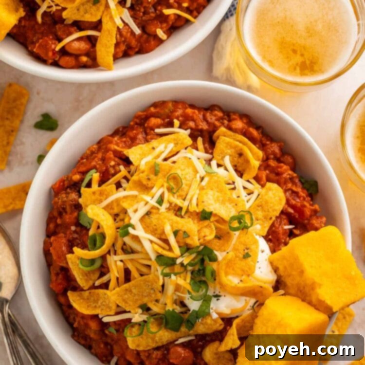 Two bowls of boilermaker chili topped with corn chips and two squares of cornbread, photographed from above.