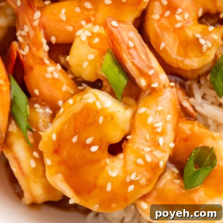Close-up of teriyaki shrimp garnished with sliced green onions and white sesame seeds.