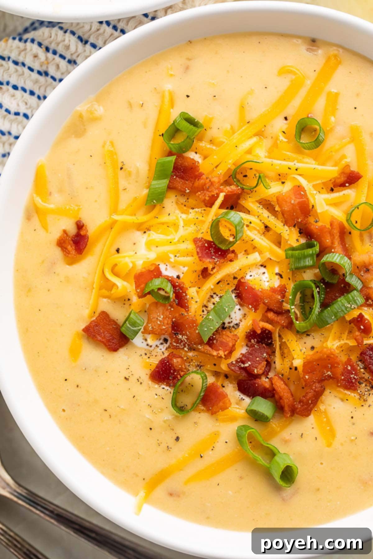 Close-up of gluten free potato soup in a large white soup bowl, garnished with fresh herbs and a swirl of cream.