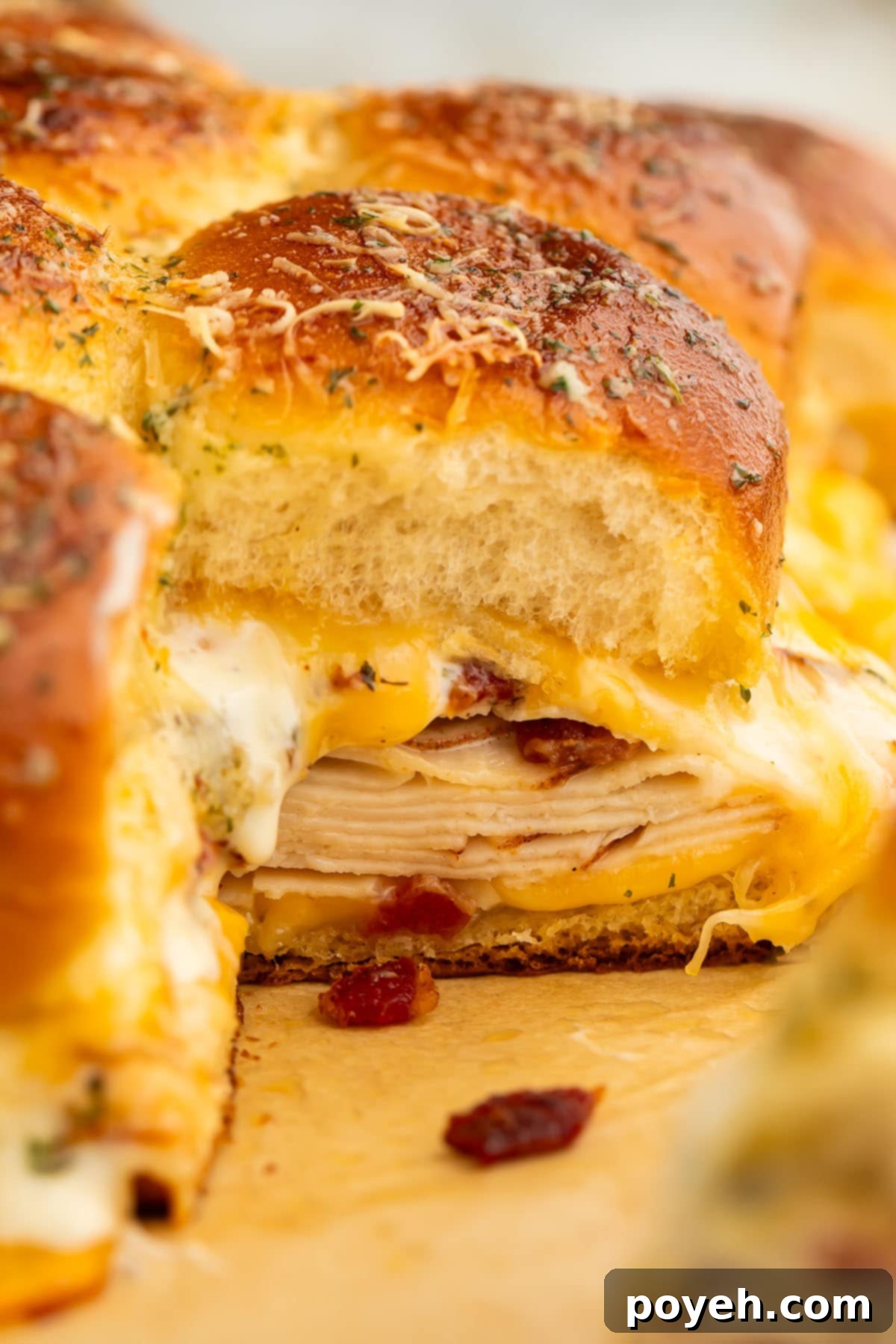 A chicken bacon ranch slider photographed from the side, revealing perfectly layered ingredients: savory deli chicken, crispy bacon, rich Colby Jack cheese, and creamy ranch dressing within a soft Hawaiian roll.