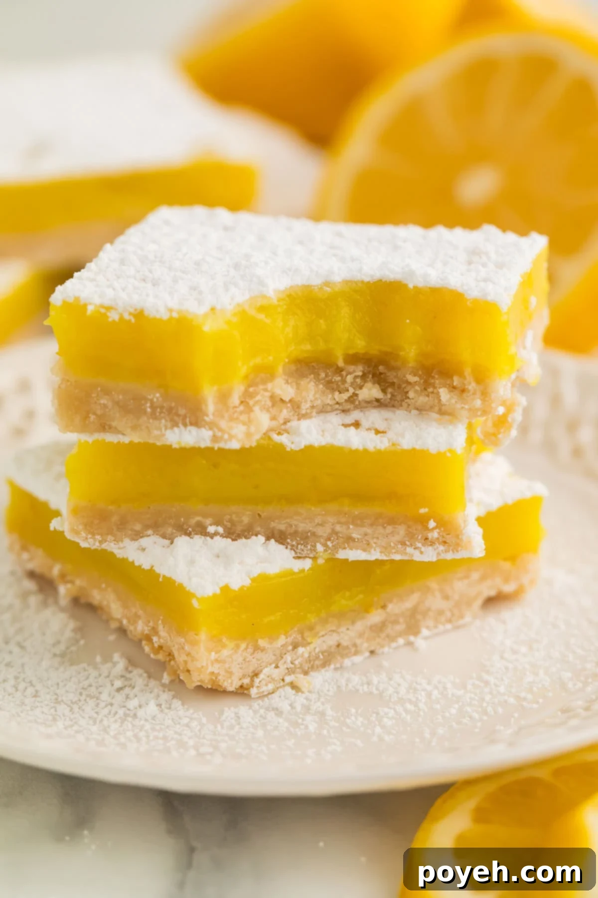 A stack of 3 vegan lemon bars, each topped with powdered sugar, on a white plate.