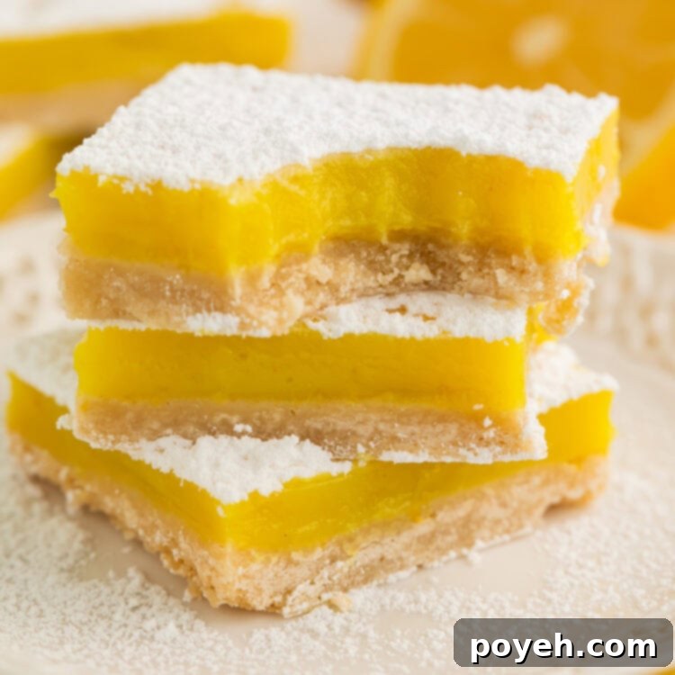 A stack of 3 vegan lemon bars, each topped with powdered sugar, on a white plate.