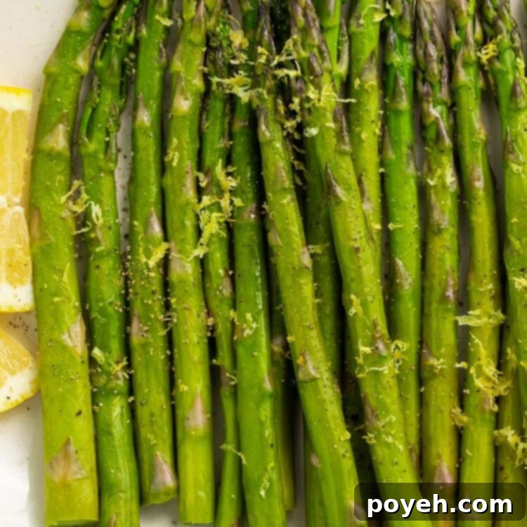 Asparagus, cooked in a sous vide, arranged on a white oval platter on a blue background.