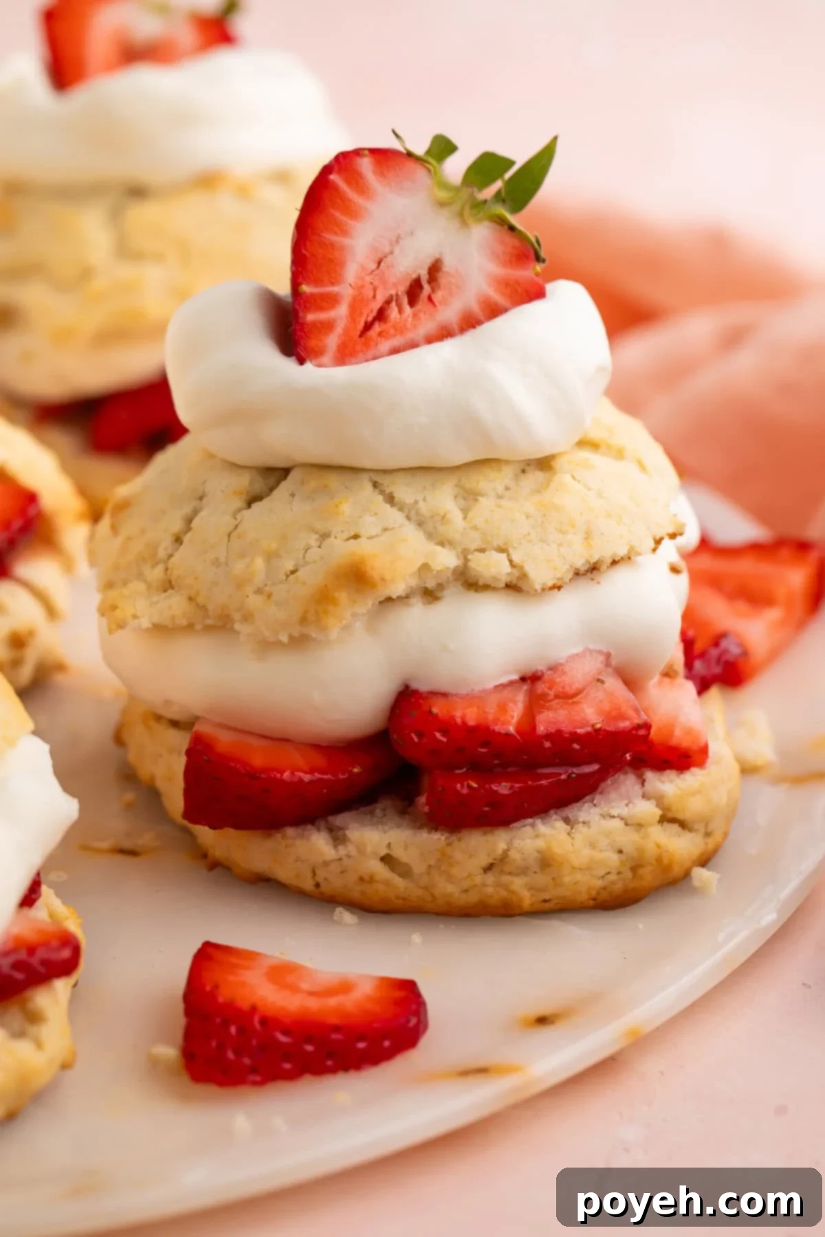 Vegan strawberry shortcake made with biscuits, sliced strawberries, and cream, beautifully arranged on a white plate.
