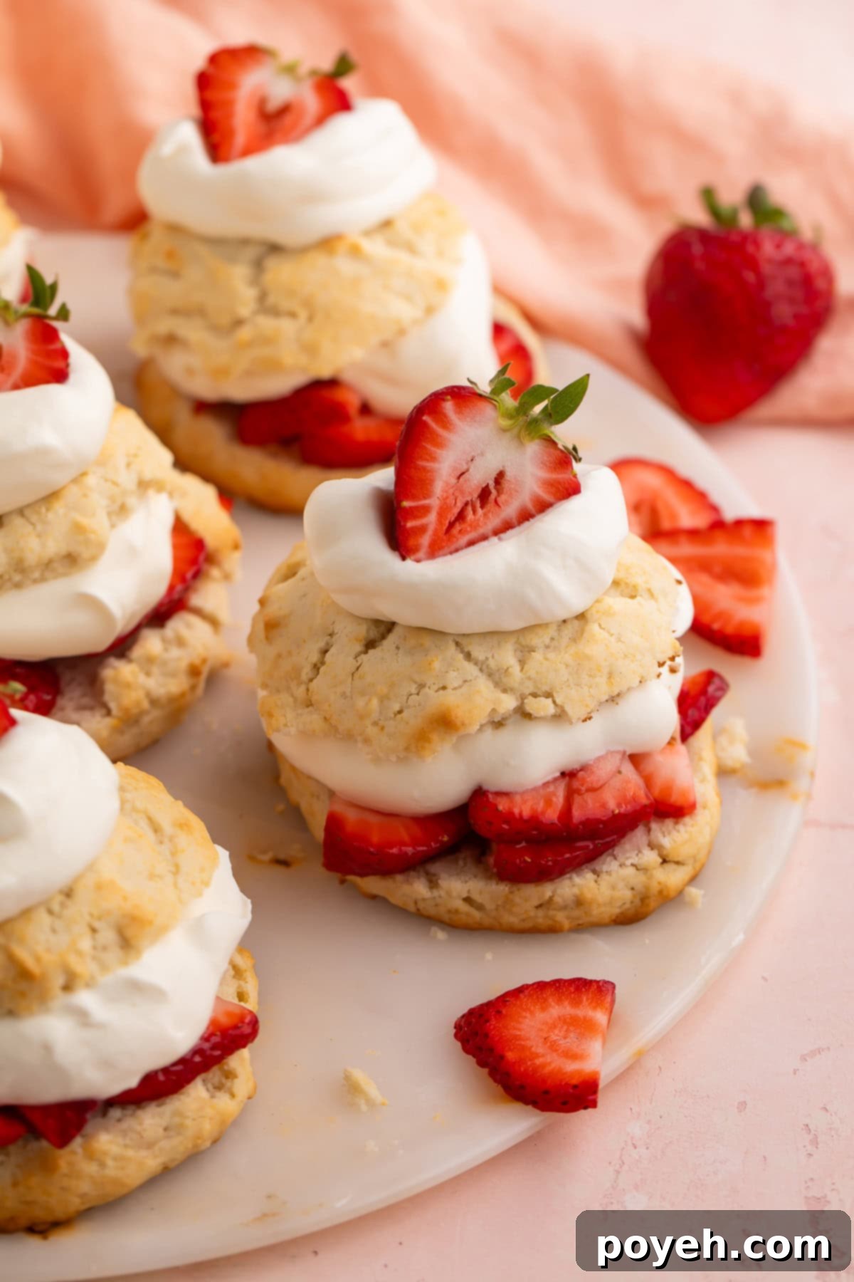 Two servings of Vegan strawberry shortcake, garnished with fresh mint leaves, against a rustic wooden background.