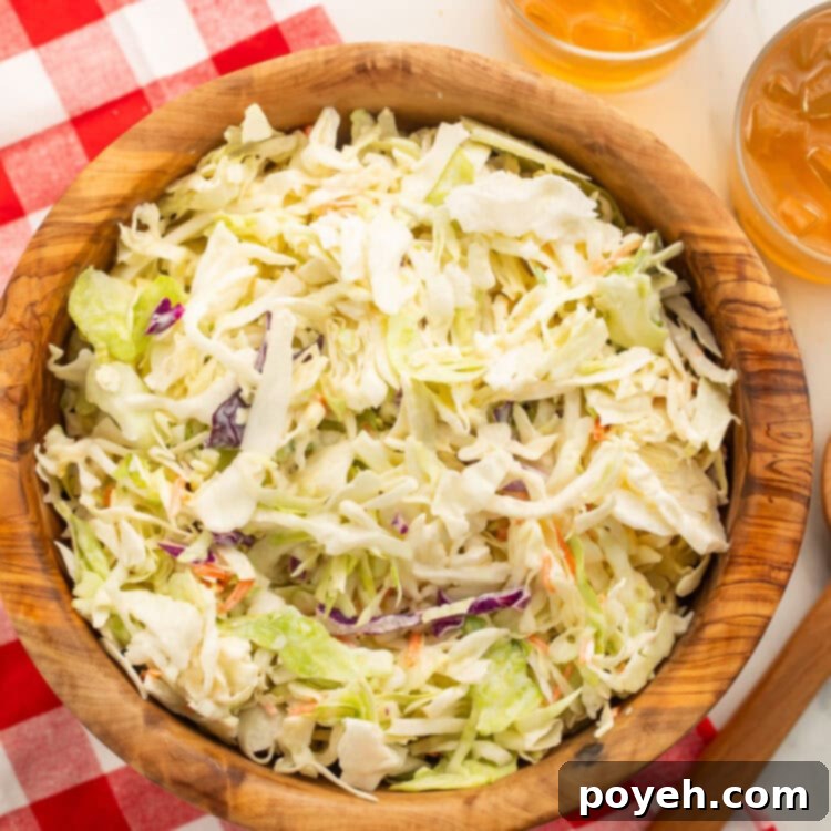 Creamy Plant-Based Slaw 4 A wooden bowl containing creamy vegan coleslaw sits on a table partially covered by a red and white checkerboard tablecloth.