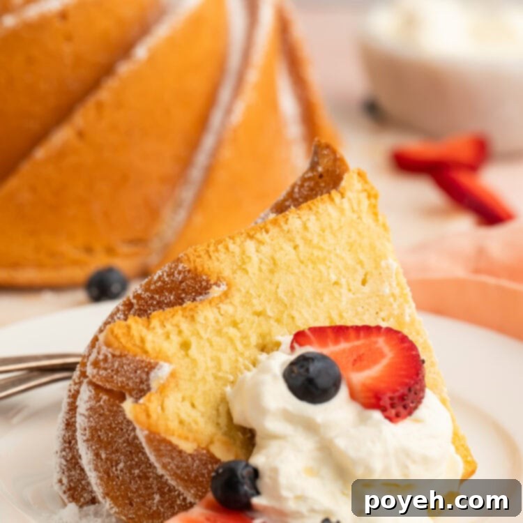 A delectable slice of Gluten Free Pound Cake on a small dessert plate with whipped cream and fresh berries, ready to be enjoyed.