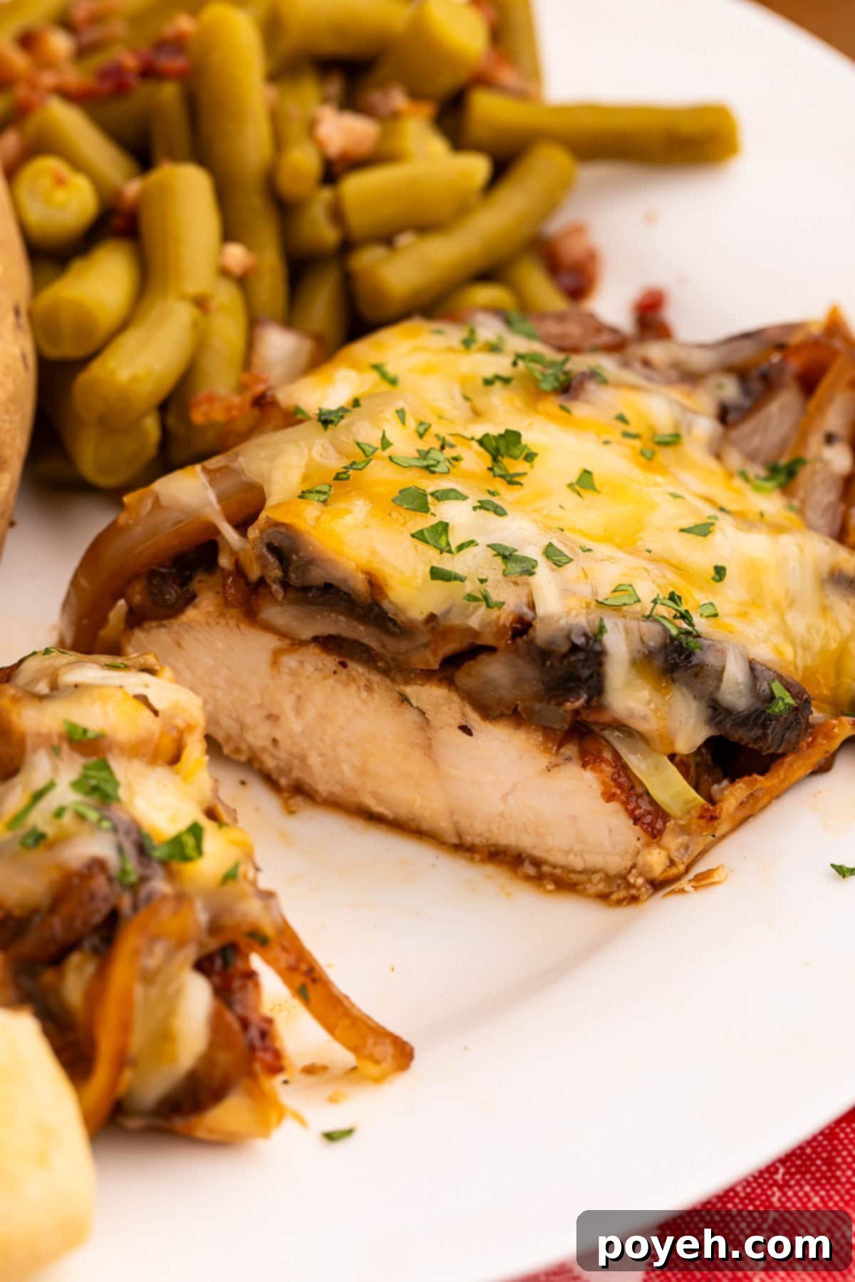 Close up of a sliced smothered chicken breast topped with onions, mushrooms and melted cheese.