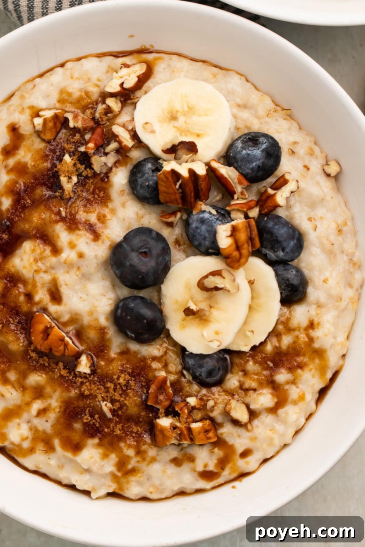 A large bowl of creamy Instant Pot Oatmeal topped with chopped pecans, sliced bananas, and fresh blueberries.