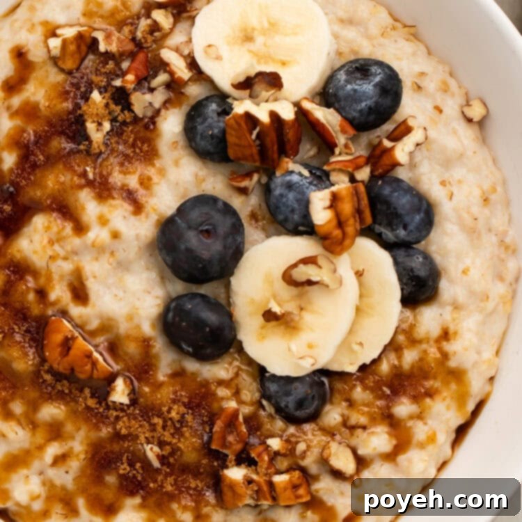 A large bowl of creamy Instant Pot Oatmeal topped with chopped pecans, sliced bananas, and fresh blueberries.