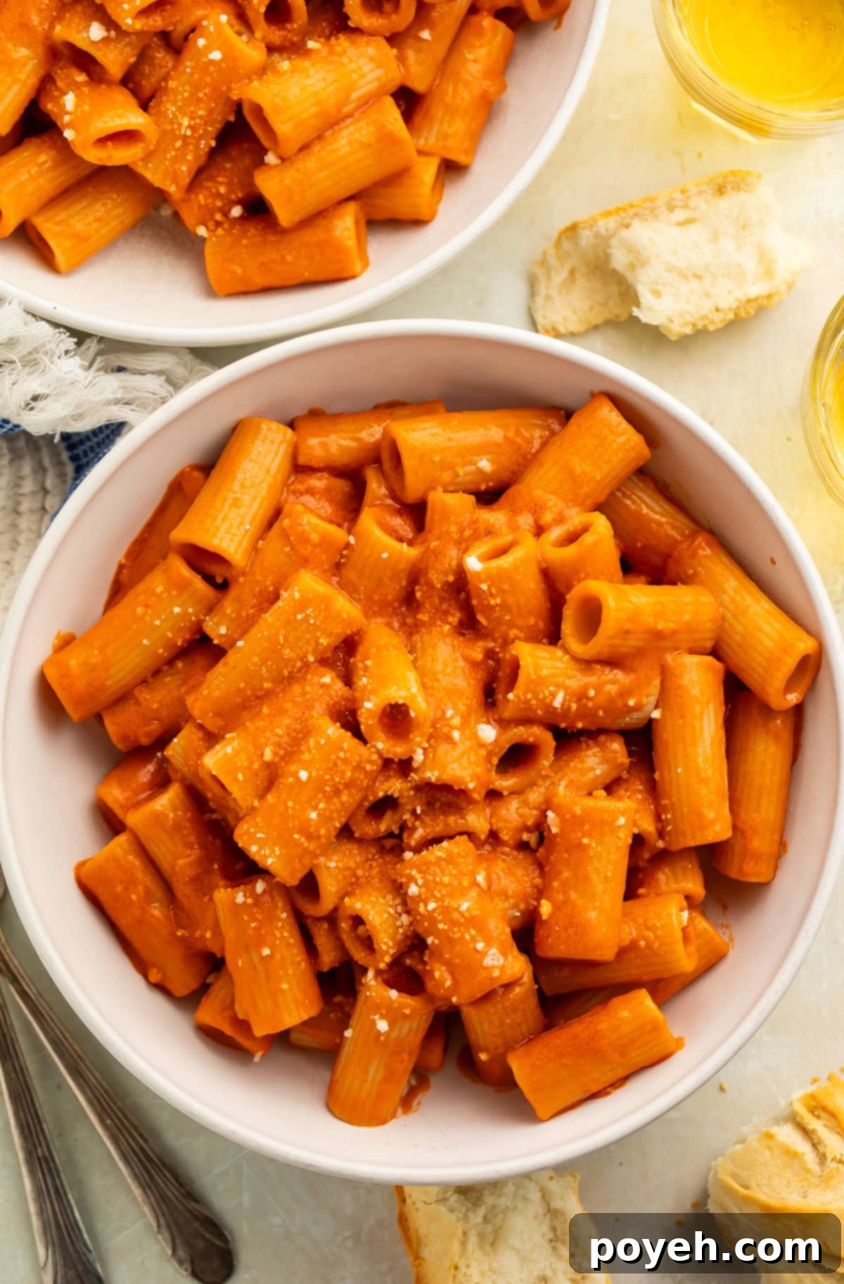 Bowl of vegan vodka pasta sauce tossed with rigatoni before being sprinkled with grated vegan parmesan.