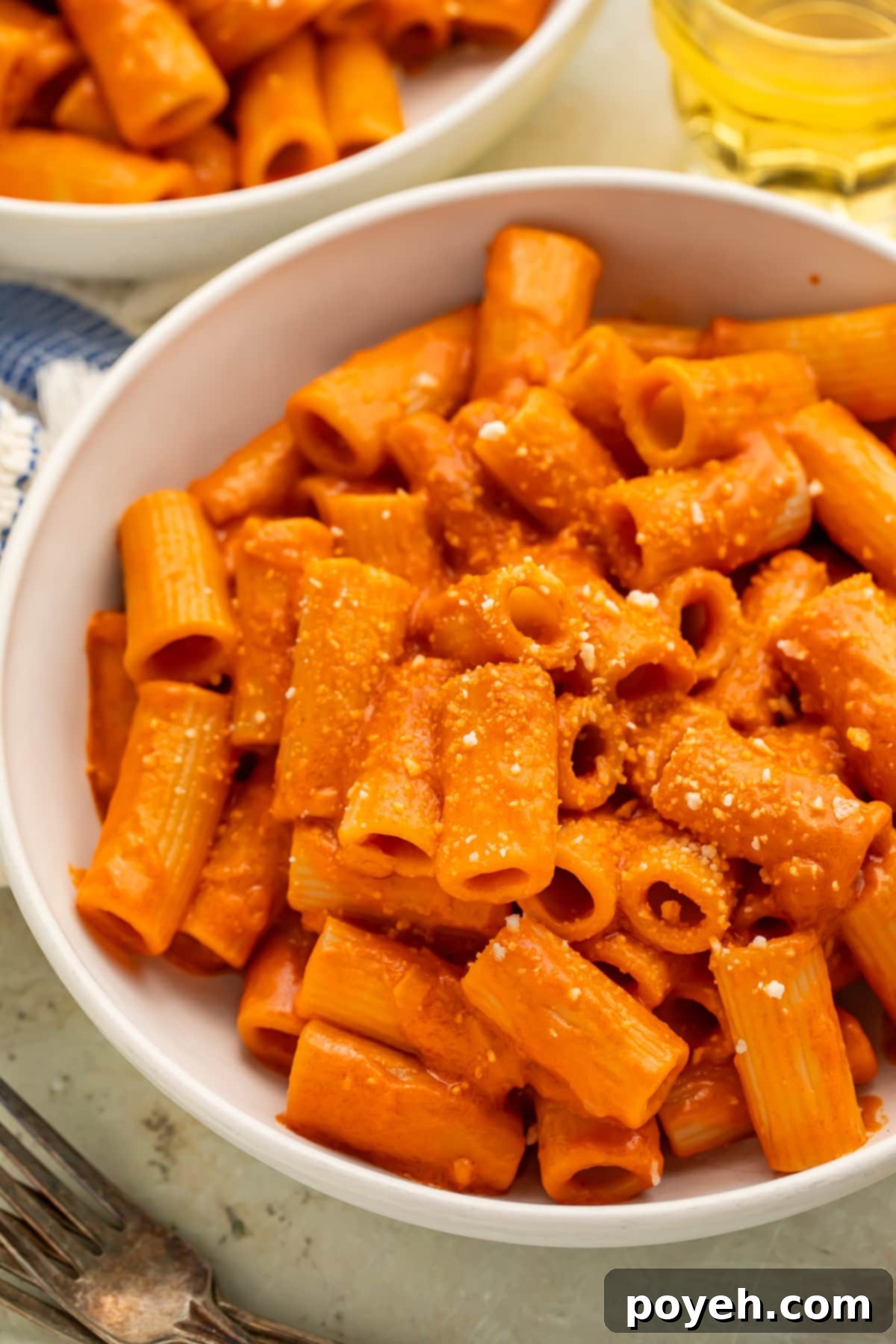 Close up of a white bowl of rigatoni pasta tossed with vegan vodka pasta sauce. 