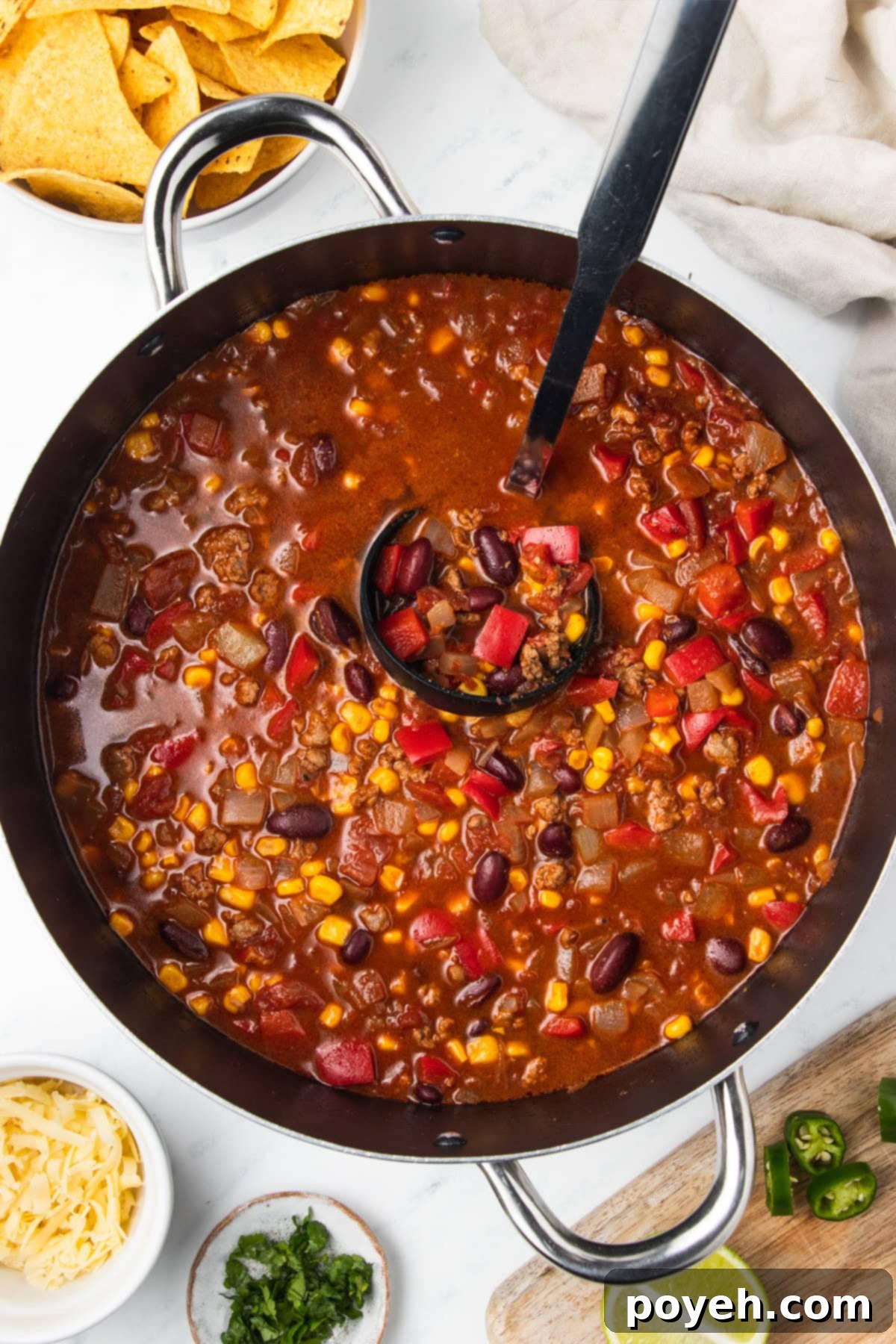 Chili with corn being ladled out of a big cooking pot.