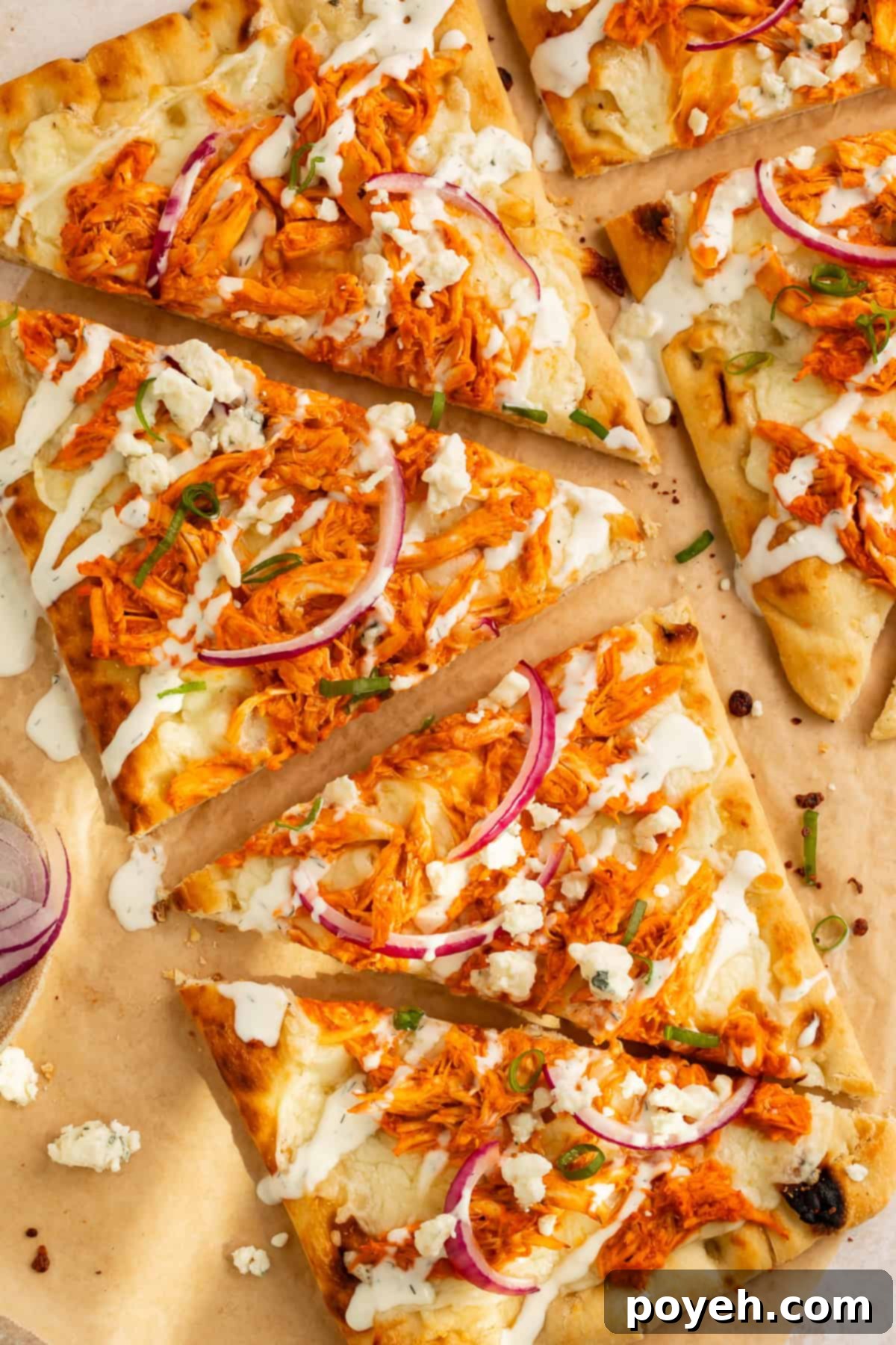 Close up of a freshly baked buffalo chicken flatbread, sliced into triangles and ready to serve, showcasing melted cheese, vibrant buffalo chicken, and fresh toppings.