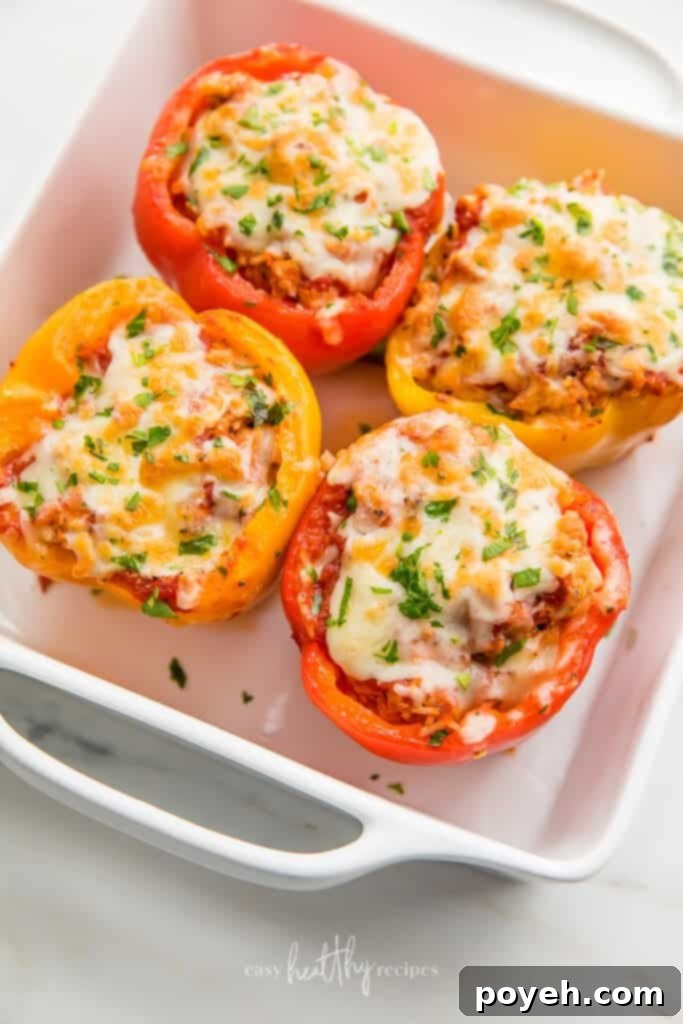Turkey Stuffed Peppers in white casserole dish topped with melted cheese and fresh parsley, close-up.