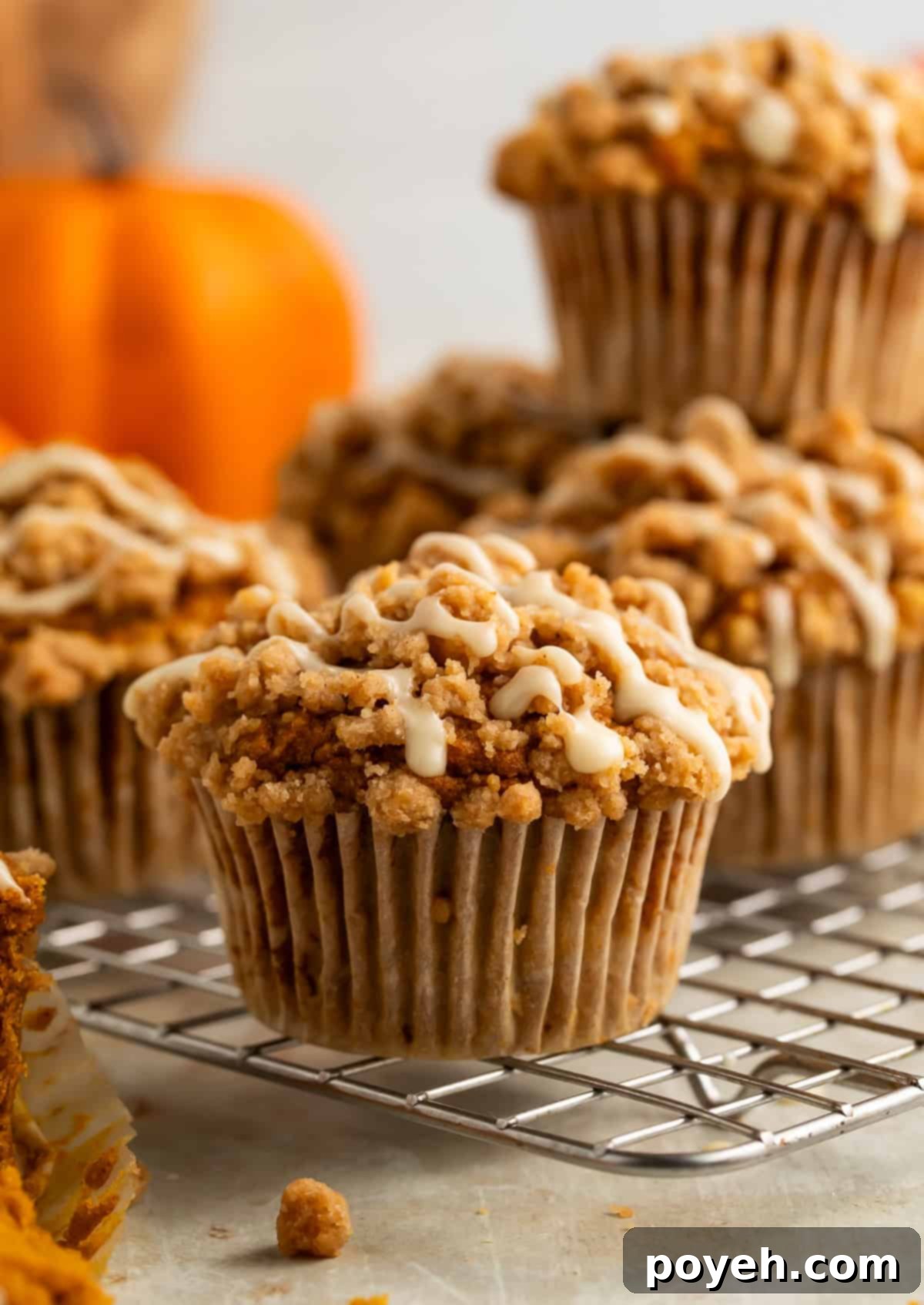 Gluten-free pumpkin muffins cooling on a wire rack, beautifully adorned with a crumbly streusel topping and a delicate drizzle of maple glaze.