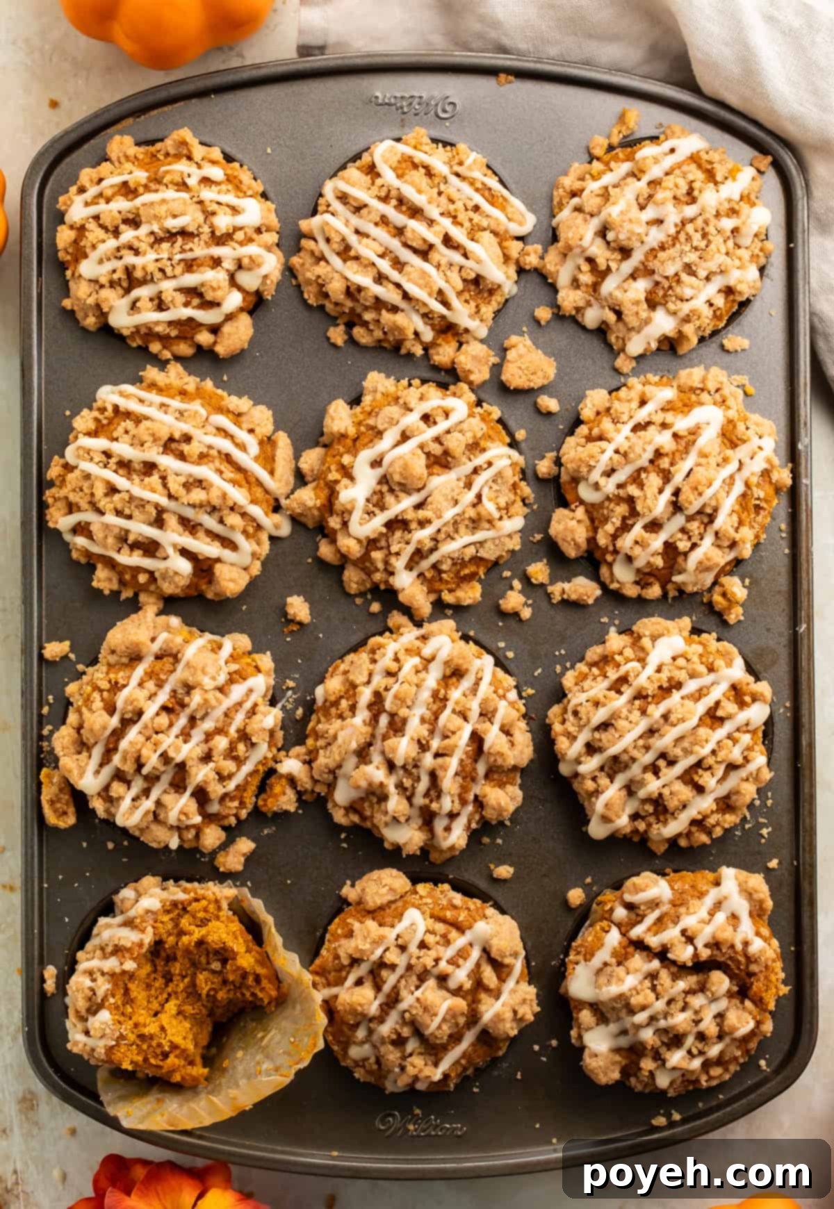 A top-down view of golden-brown gluten-free pumpkin streusel muffins still in the muffin pan, ready to be enjoyed. The streusel topping is visible on each one.