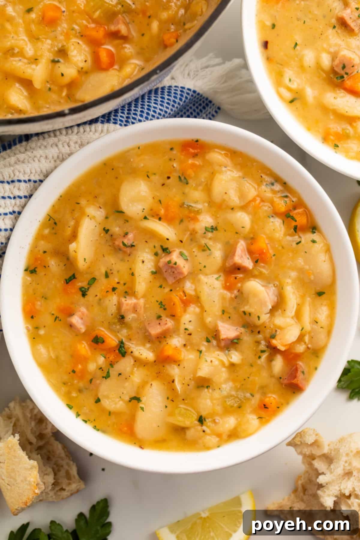 Close up of a white bowl of lima bean soup with another bowl and the casserole pot visible off to the side.