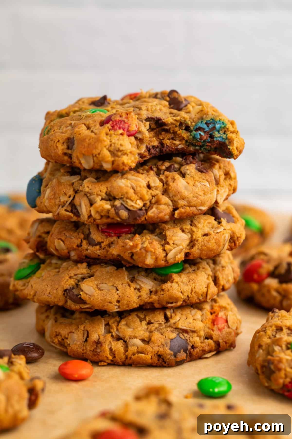 Close up of a stack of golden brown monster cookies with a bite taken out of the top one, revealing the rich interior.